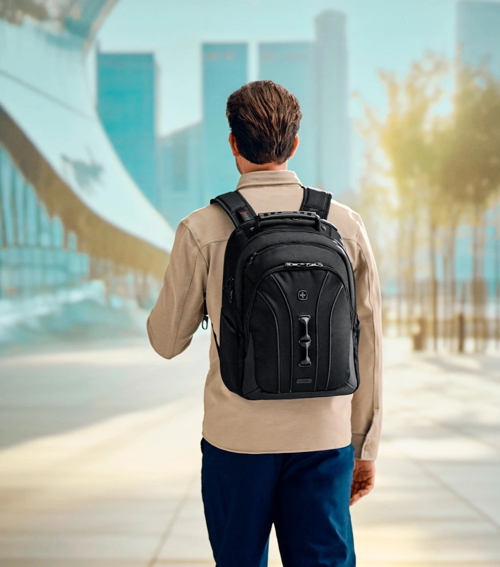 Man with backpack walking in a city, seen from the back, urban background