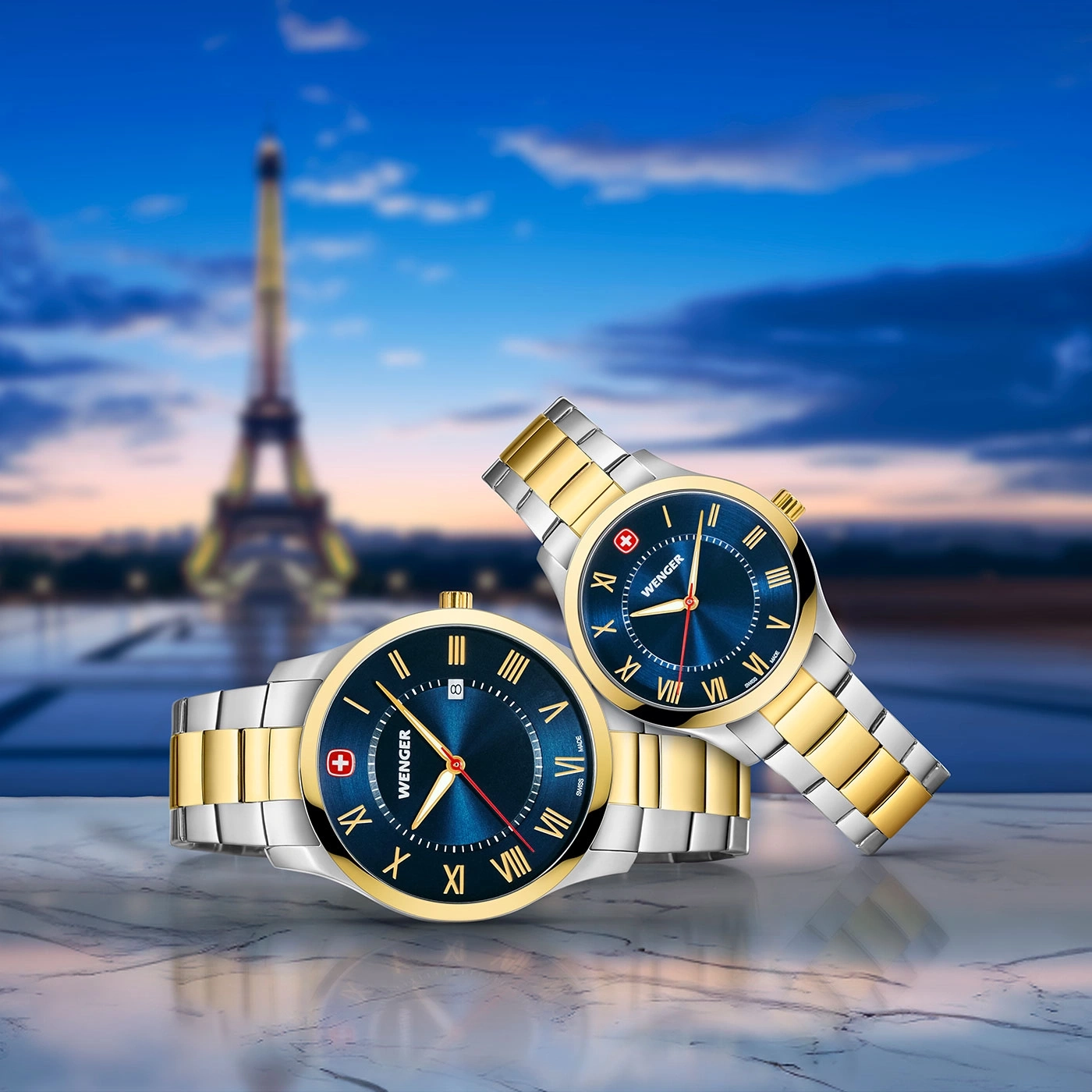 Two Wenger watches with blue dials and Roman numerals in front of the Eiffel Tower.