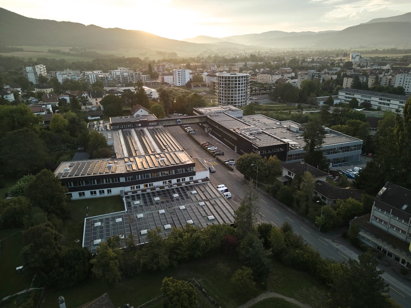 Aerial view of an industrial area with solar panels and mountains in the background at sunset.