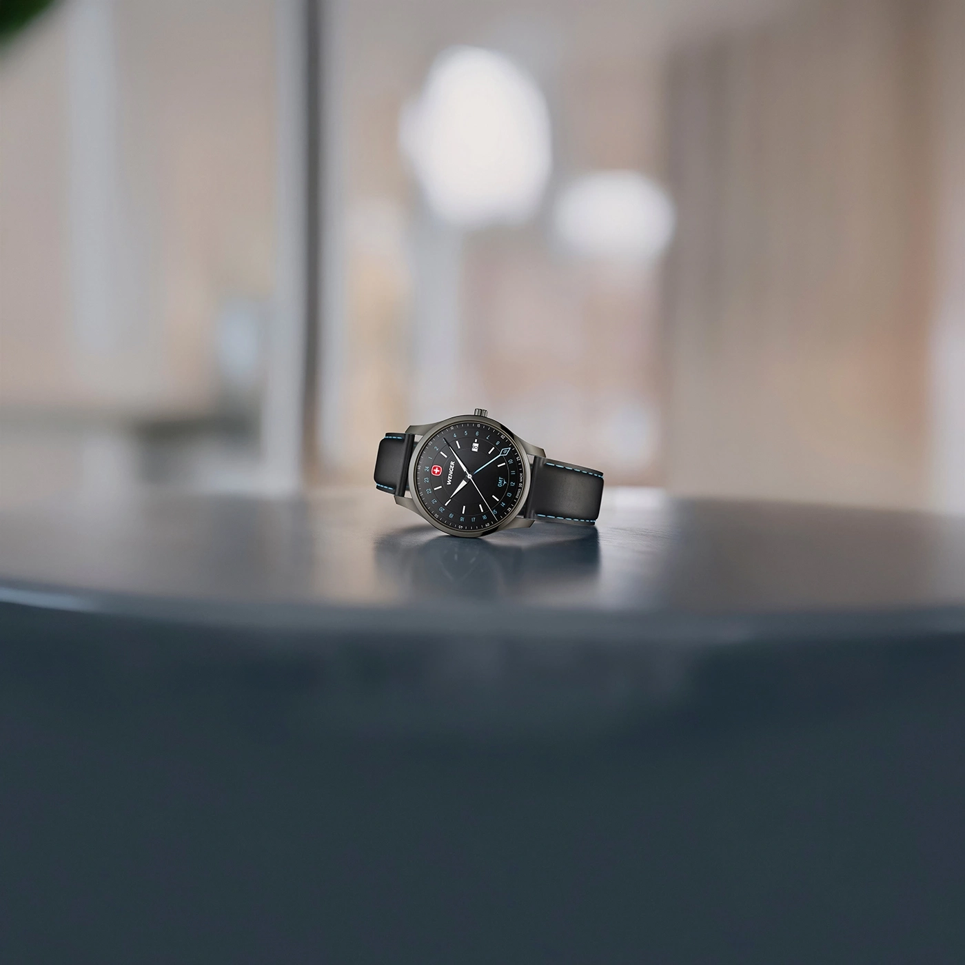 A Wenger wristwatch on a dark table with a blurred background.