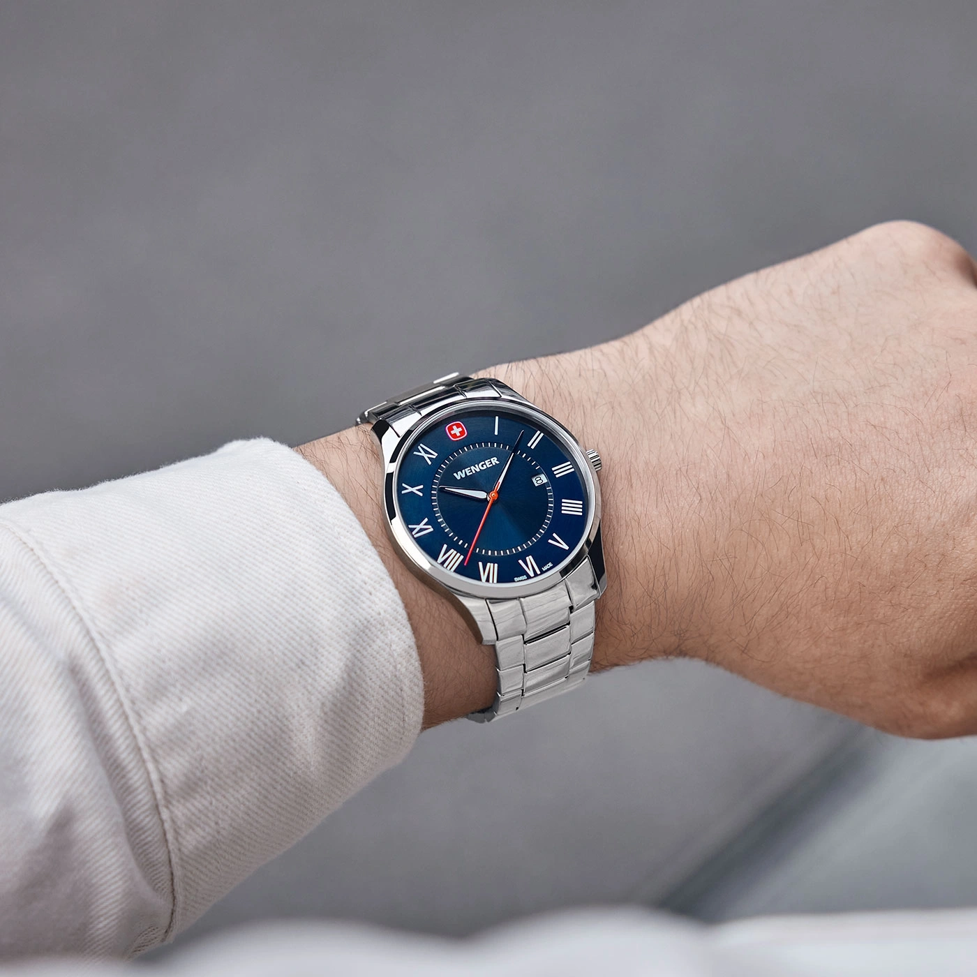 Wristwatch on wrist, blue dial, silver band, Wenger brand, close-up shot